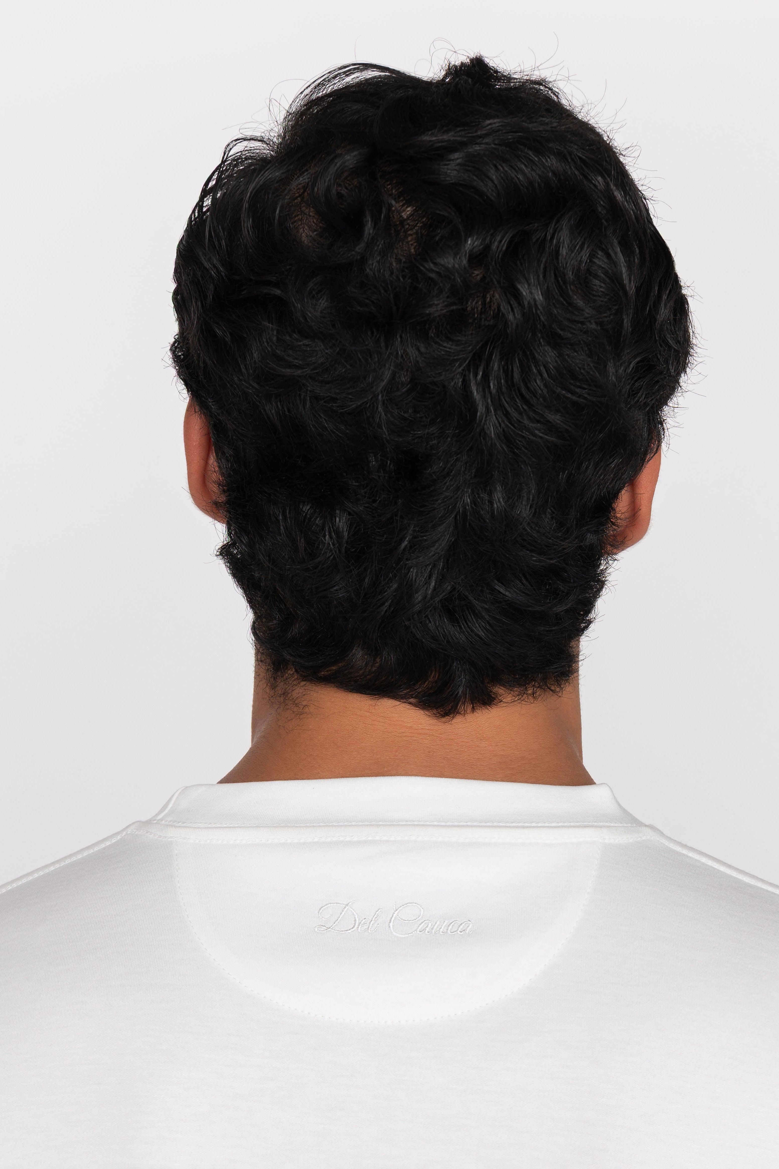 Person wearing a white shirt with a plain background
