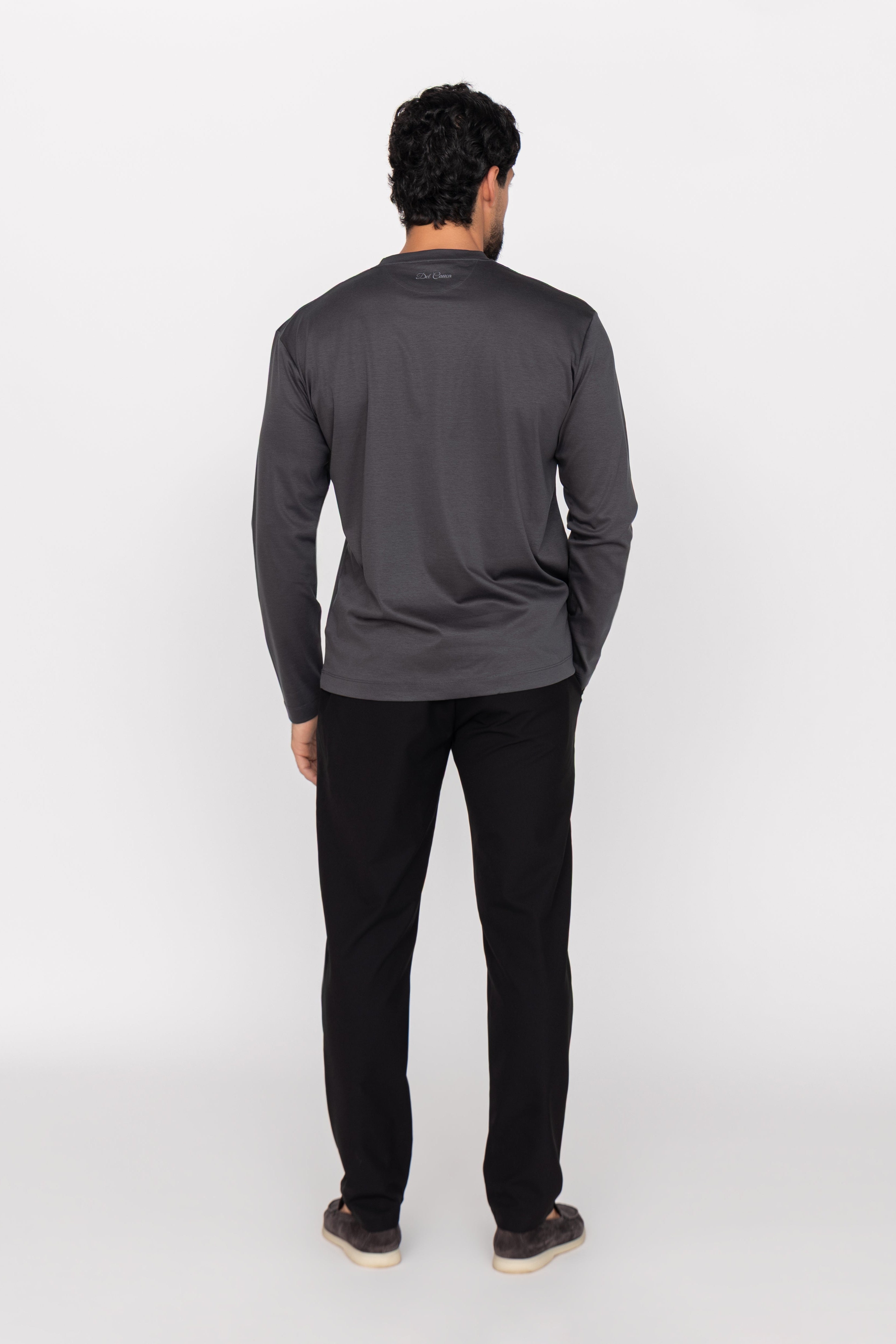 Person wearing a dark gray long-sleeve shirt and black pants on a white background