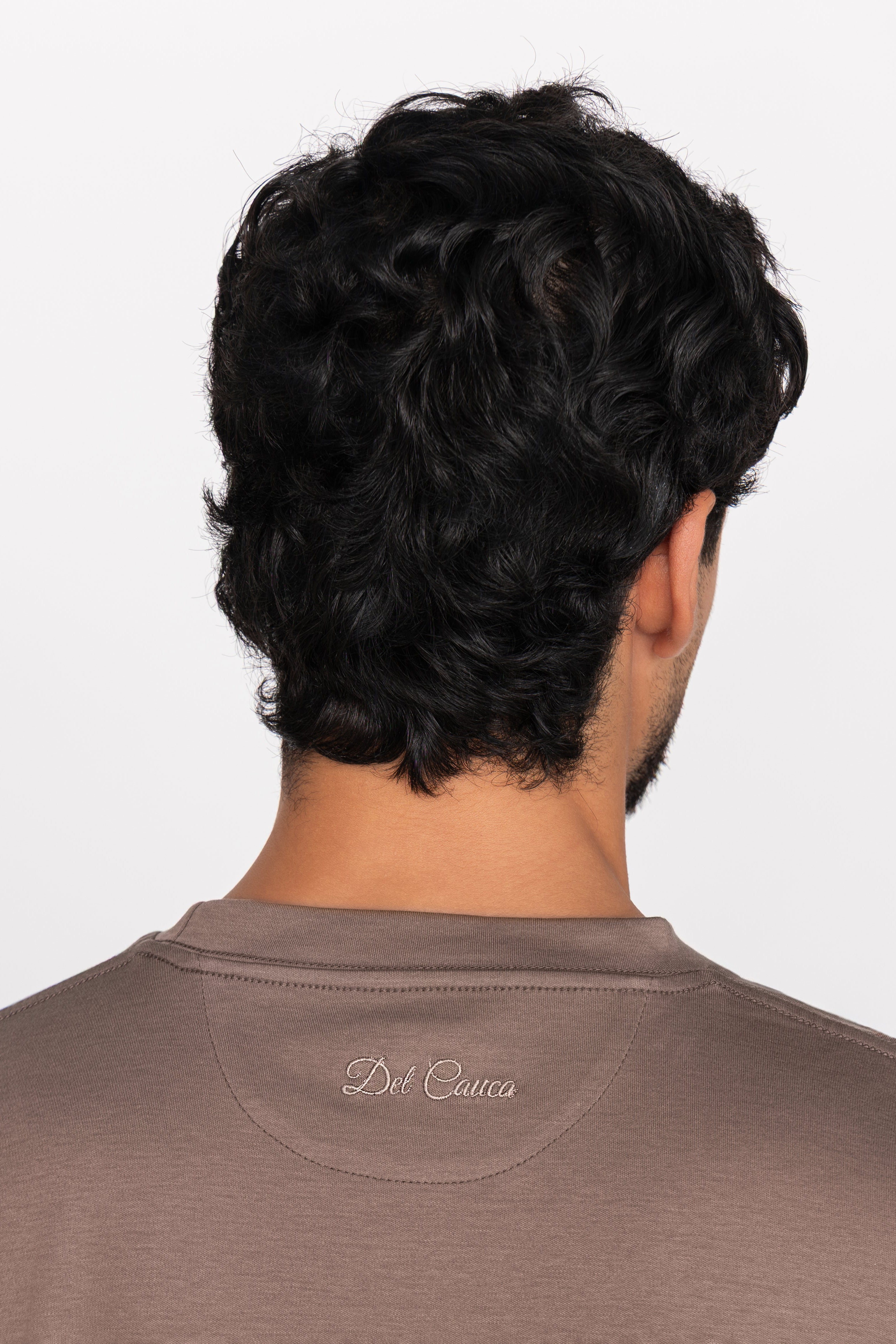 Person wearing a brown shirt with 'Del Core' branding on a white background