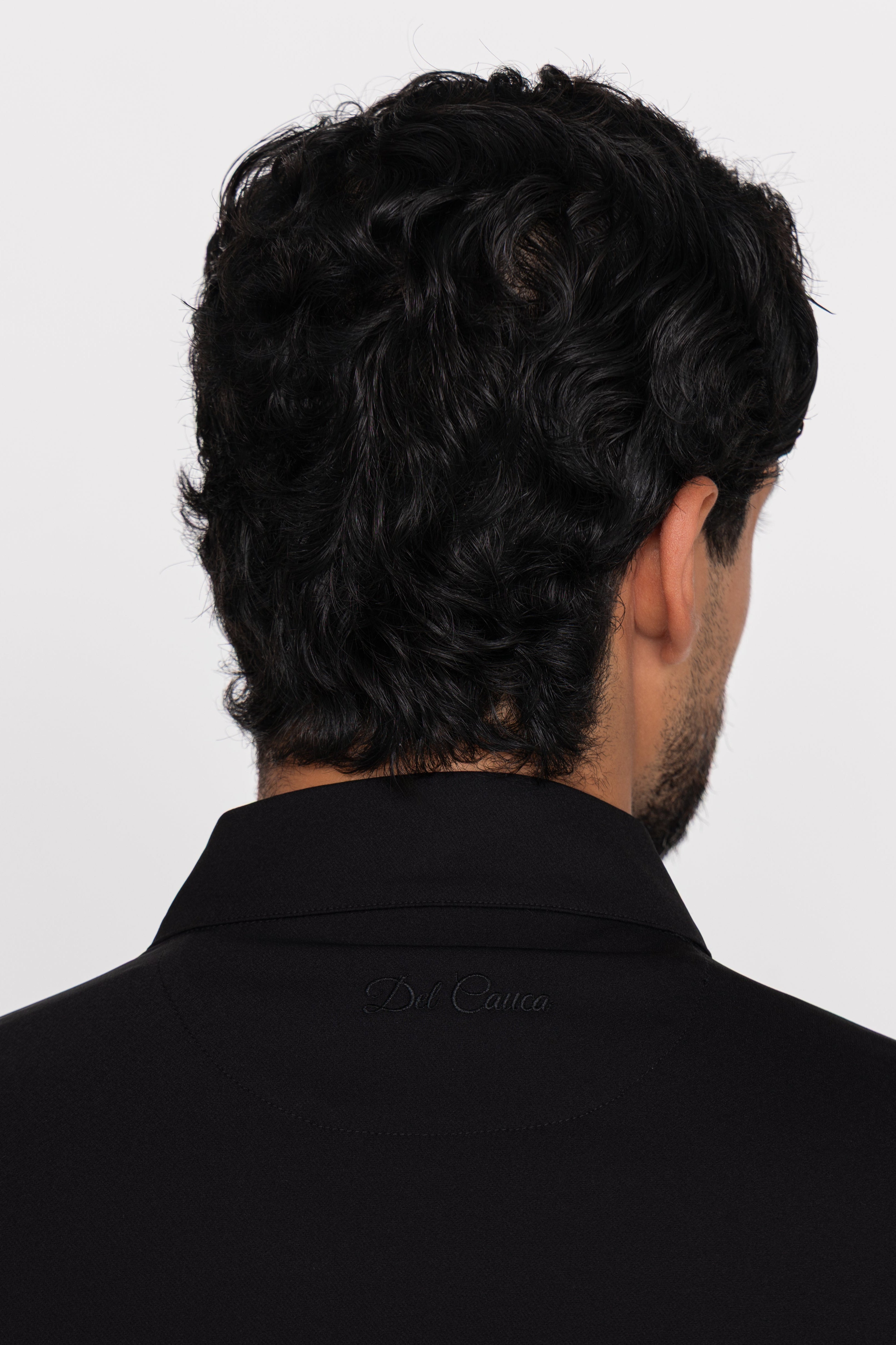 Person wearing a black shirt with a brand logo on a white background