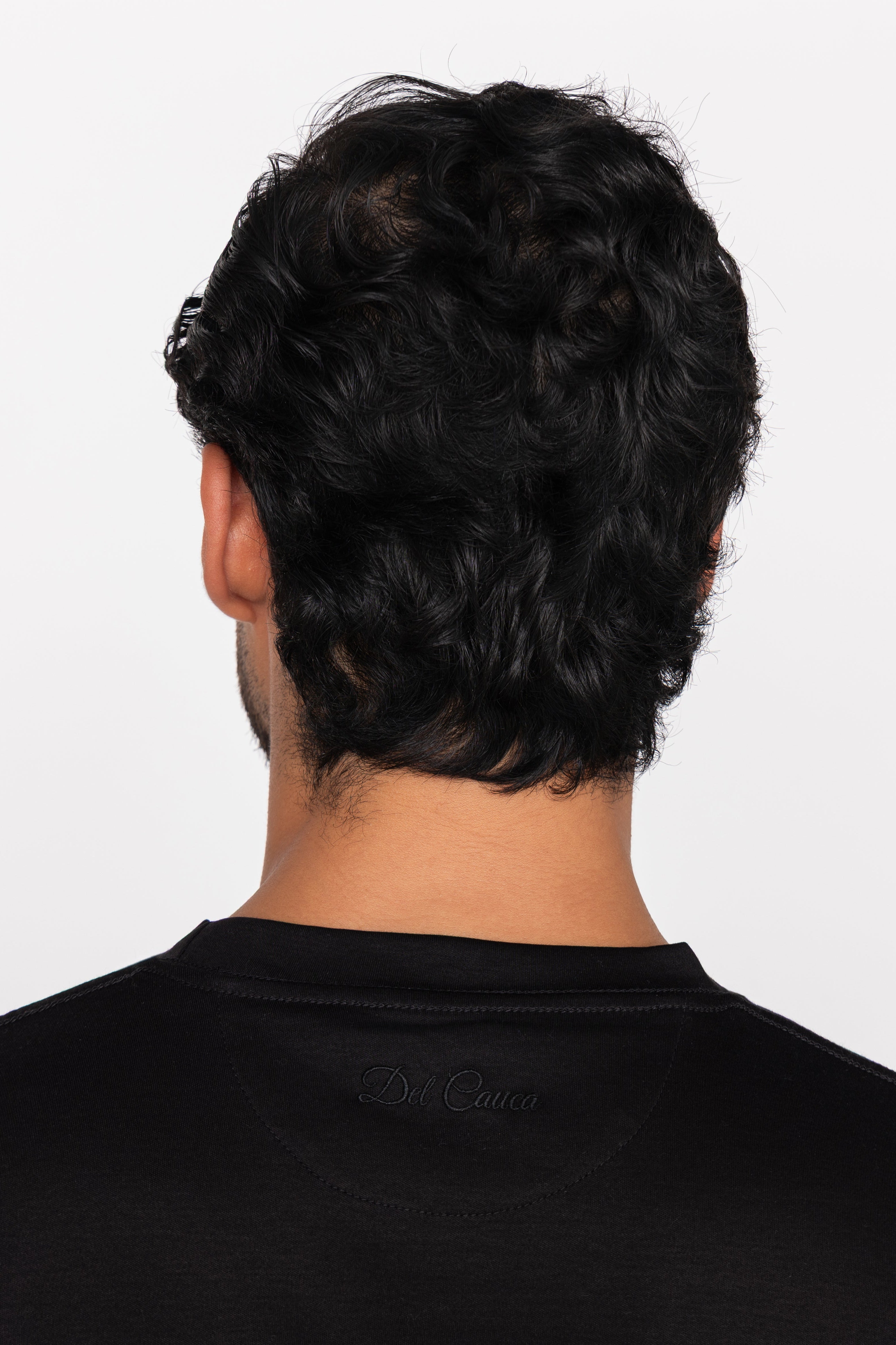 Person wearing a black shirt with a brand logo on a white background