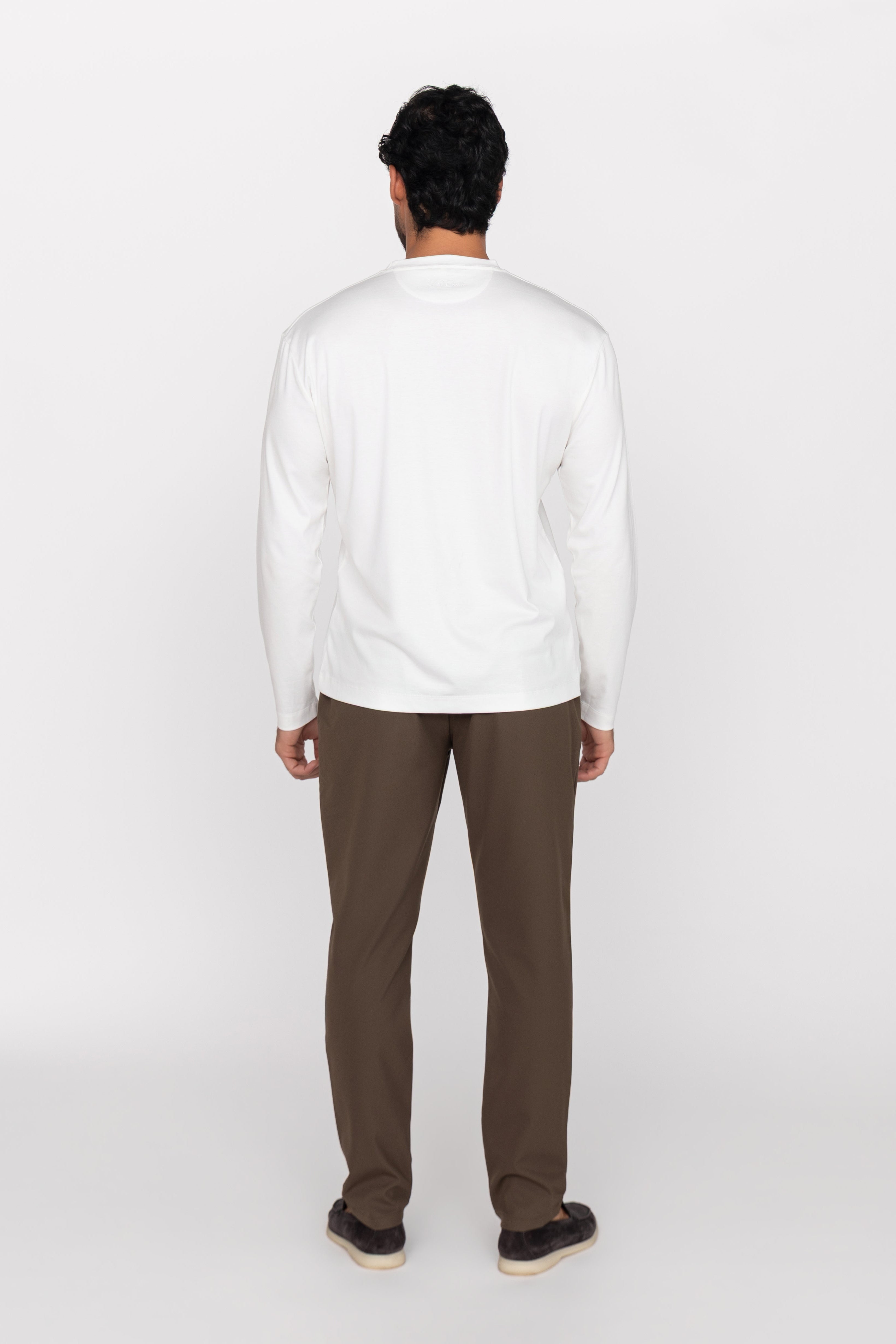 Person wearing a white sweater and brown pants on a white background